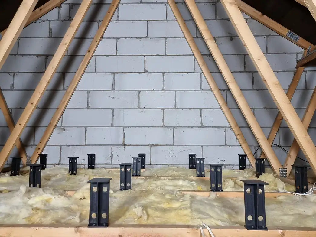 Attic insulation with wooden beams and a concrete wall and Loft Leg supports